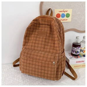 Close-up of brown plaid corduroy backpack featuring leather logo and side water bottle pocket