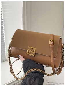 Détail du sac à rabat en cuir caramel avec texture plissée et boucle dorée géométrique