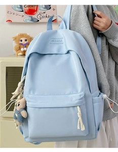 Close-up of light blue backpack with rope zippers and cute plush bear charm detail