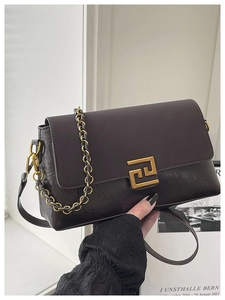 Vue détaillée du sac à rabat vintage marron foncé avec texture cuir brillant et fermoir doré