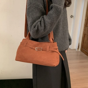 Retro brown suede tote bag with decorative buckle strap worn by a female model