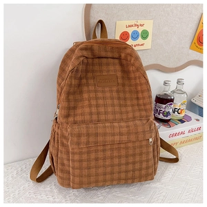 Close-up of brown corduroy backpack showing fine checkered texture and leather brand label