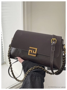 Gros plan sur un sac bandoulière en cuir marron avec boucle métallique géométrique dorée