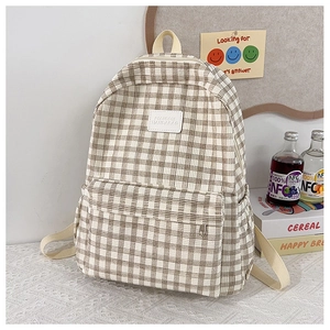 Detail view of plaid canvas backpack featuring zip pockets and stylish leather logo label