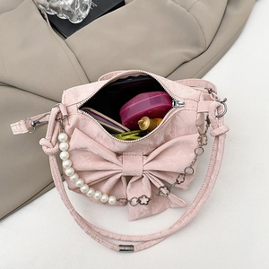 Sac rose à nœud avec chaîne en perles et texture en tissu vu de dessus