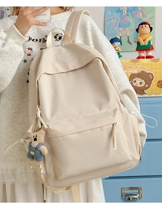 Detail of off-white nylon backpack featuring a front zipper pocket and cute bear pendant