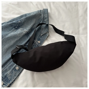 Détail du sac bandoulière étanche noir posé sur une veste en jean décontractée