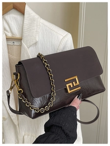 Détail d'un sac bandoulière marron foncé avec textures cuir et boucle dorée élégante