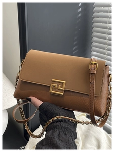 Détail d'un sac à bandoulière en cuir marron avec texture brillante et boucle dorée
