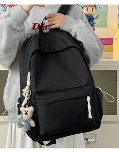 Close-up of black nylon backpack with a cute bear charm and woven rope zipper pull