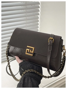 Détail d'un sac bandoulière vintage marron avec boucle dorée et bandoulière chaîne