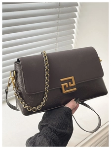 Détail de la texture cuir marron foncé et de la boucle dorée sur le sac à bandoulière