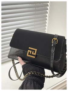 Détail du sac bandoulière noir avec rabat en daim, cuir brillant et boucle en métal doré