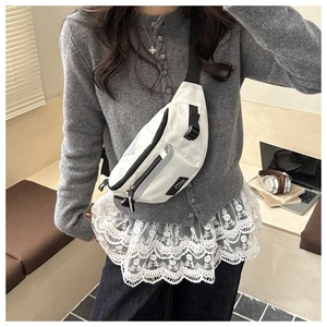 Détail d'un sac bandoulière en nylon blanc avec sangle noire réglable en mode lifestyle