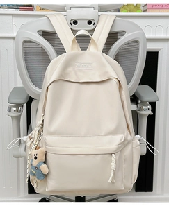 Close-up of off-white backpack featuring a cute bear pendant and XINFEIDA embroidery