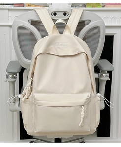 Detail view of cream white nylon backpack featuring woven zipper pulls and side pockets
