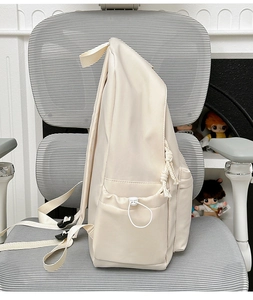 Detail view of cream nylon backpack with adjustable straps and drawstring side pockets