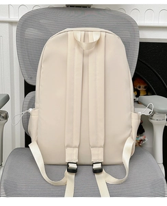 Detail view of wide padded shoulder straps on a minimalist off-white nylon backpack