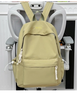 Detail of light green waterproof nylon backpack with yellow embroidery and rope zippers