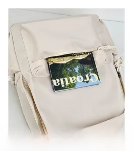 Close-up of front pocket on beige nylon backpack holding a magazine to show storage space