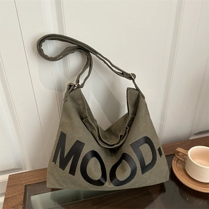 Army green canvas shoulder bag with MOOD lettering on a wooden coffee table