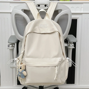 Minimalist cream white nylon backpack featuring a plush bear charm and embroidery detail