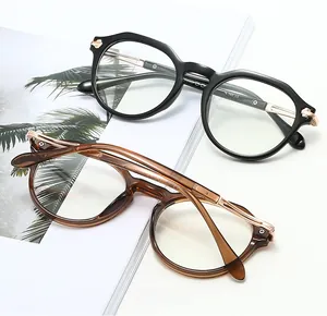 Close-up of retro oval TR90 eyewear frames in black and amber brown with metal hinges