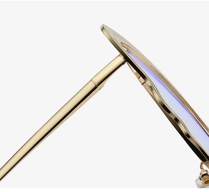 Close-up of golden metal hinge and blue light coating on butterfly fashion glasses