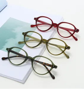 Close-up of retro oval glasses frames in green and red with classic double-dot metal rivets