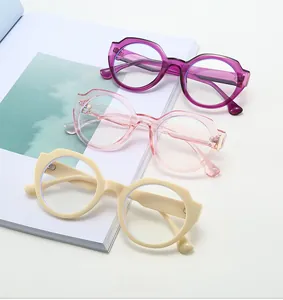 Trois paires de lunettes ovales à monture épaisse en violet, rose et beige sur un magazine