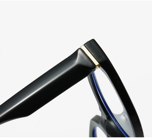 Détail des charnières dorées et verres anti-lumière bleue sur monture ovale noire