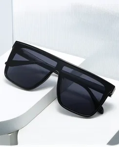 Detail shot of black oversized flat top sunglasses on a minimalist white display