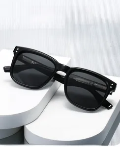 Détail de lunettes de soleil noires carrées avec clous argentés sur socle géométrique
