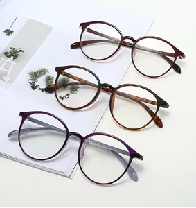 Three retro round glasses frames in burgundy, tortoiseshell, and lavender on a magazine