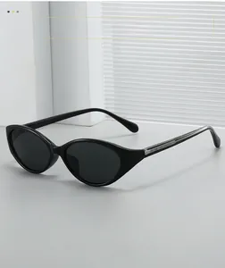 Close-up of sleek black cat-eye oval sunglasses with high-gloss frame on minimalist stand