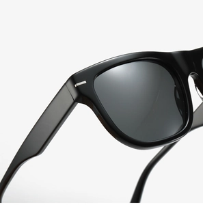 Macro shot of glossy black frame edge and silver metal hinge detail on sunglasses