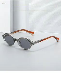 Detail view of oval grey frames with amber orange temples on a modern pedestal