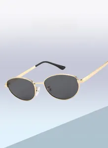 Primer plano de gafas de sol cat-eye con montura metálica dorada y lentes oscuras