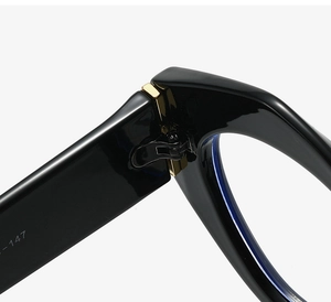 Detail of sturdy gold-toned metal hinges on thick black oval frame glasses