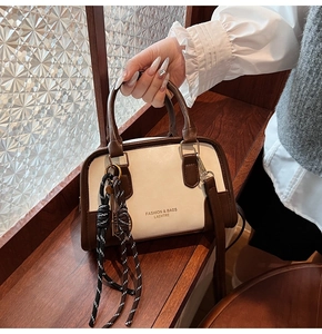 Detail of color-block faux leather handbag featuring brown handles and branded logo text