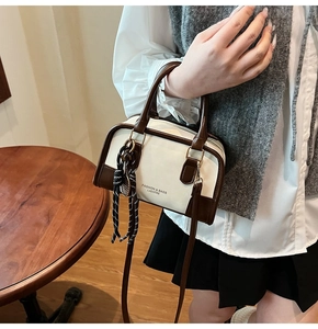 Detail of vintage beige and brown bowling bag with a decorative scarf and long strap