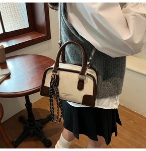 Detail of retro color-block boston bag showing cream and brown leather finish