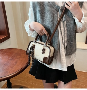 Detail of a contrast color Boston bag with a checkered silk scarf and crossbody strap