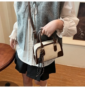 Detail of retro cream boston bag with contrast straps and a decorative striped ribbon