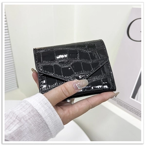 Detail of black glossy crocodile pattern three-fold wallet with envelope flap closure