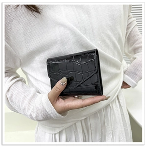 Detail of black faux crocodile patent leather envelope wallet held in hand
