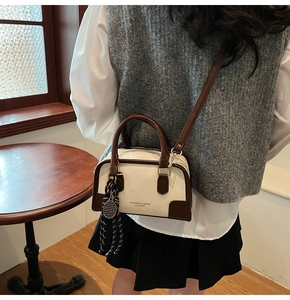 Detail of a minimalist two-tone crossbody bag with silk scarf and long shoulder strap