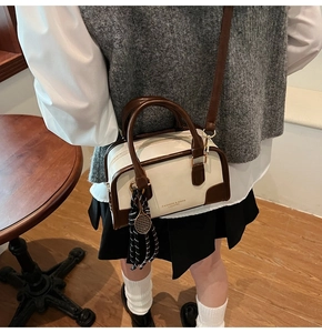 Retro cream crossbody bag with brown accents and tennis racket charm in a cafe setting