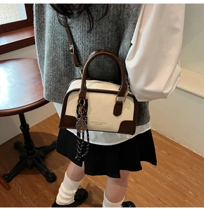 Detail of a contrast boston bag with top handles, silk scarf accent, and long shoulder strap