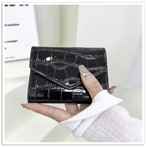 Primer plano de una mini cartera negra de charol con grabado de cocodrilo